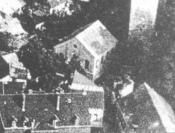 Ausschnitt aus einer Luftbildaufnahme, auf der die Synagoge eher zufällig  zu sehen ist. Gut erkennbar ist die umgebende Bebauung,  u.a. rechts oben der Stumpfe Turm. Stadtarchiv Aschersleben.